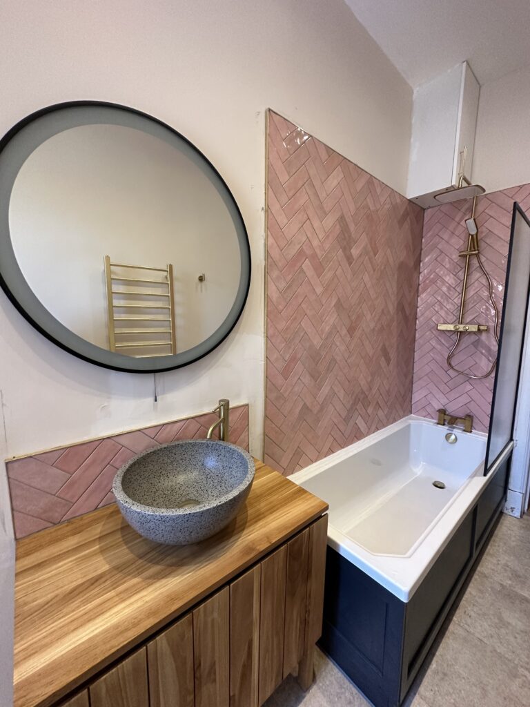 Luxury bathroom renovation in Newton Mearns with pink wall panels, vanity unit and round mirror