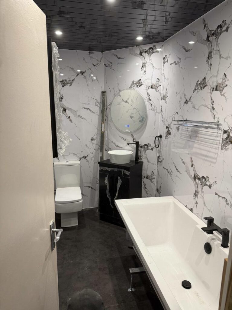 Completed luxury bathroom renovation Glasgow - marble effect tiles, freestanding bath, black vanity and LED mirror