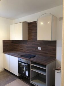 Renovated white kitchen with timber-effect splashback — Glasgow