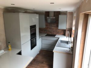 White handleless kitchen with brick-effect splashback — Glasgow renovation