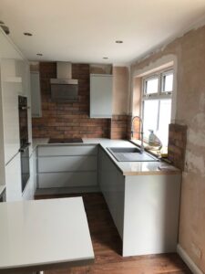 Grey handleless kitchen with exposed brick splashback — Glasgow renovation