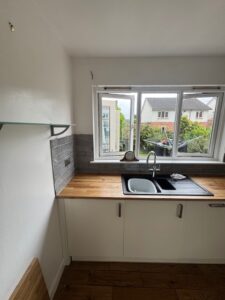White shaker kitchen with timber worktop and garden view — Glasgow